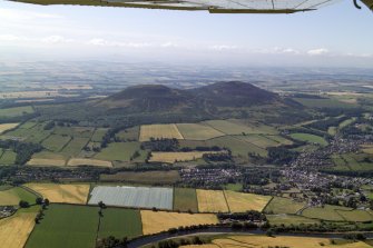General oblique aerial view centred on the remains of the fort and the Eildon Hills with the town in the foreground, taken from the NNW.