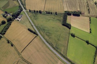 Oblique aerial view centred on the cropmarks of the Roman temporary camps and possible fort annexe, taken from the NW.