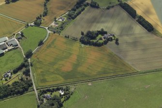 Oblique aerial view centred on the cropmarks of the enclosures and possible building with the manse and remains of the abbey adjacent, taken from the NE.