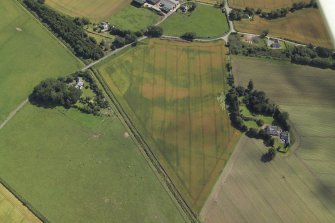 Oblique aerial view centred on the cropmarks of the enclosures and possible building with the manse and remains of the abbey adjacent, taken from the WNW.