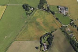 Oblique aerial view centred on the cropmarks of the enclosures and possible building with the manse, farmsteading, farmhouse and remains of the abbey adjacent, taken from the WSW.