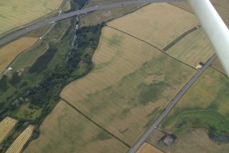 Oblique aerial view centred on the cropmarks of the fort, taken from the NE.