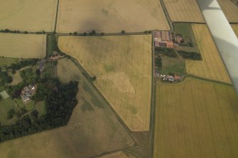 Oblique aerial view centred on the cropmarks of the field boundary and the cropmarks of the quarry with the farmhouse, farmsteading, country house, walled garden and dovecot adjacent, taken from the WSW.