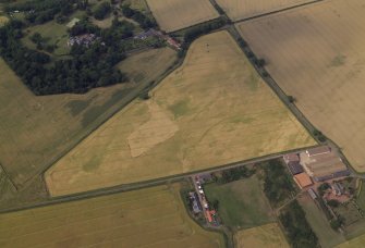Oblique aerial view centred on the cropmarks of the field boundary and the cropmarks of the quarry with the farmhouse, farmsteading, country house, walled garden and dovecot adjacent, taken from the S.