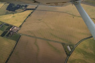 General oblique aerial view centred on the linear cropmarks with the cropmarks of the quarry, frost wedges, linear cropmarks, farmsteading and farmhouse adjacent, taken from the SE.