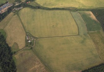 Oblique aerial view centred on the cropmarks of the henge with the farmhouse and farmstead adjacent, taken from the WSW.