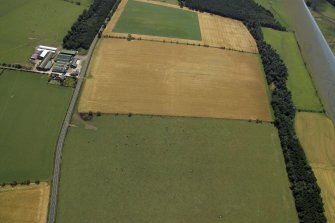 Oblique aerial view centred on the cropmarks of the settlement and barrow, taken from the NNW.