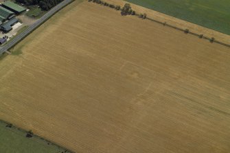 Oblique aerial view centred on the cropmarks of the settlement and barrow, taken from the WNW.