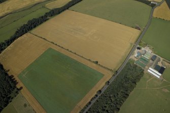 Oblique aerial view centred on the cropmarks of the settlement and barrow, taken from the ESE.