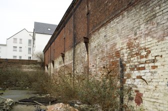 S side. View from SE showing communal wall, adjoining building having been demolished, note the remains of cast-iron wall brackets from the adjacent property now demolished. The frame of the copper works appears to be timber (note wall head beam).