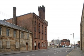 General view from SSE of paint works at 108-118 Tradeston Street, corner of Cook Street, note parapet, machiolation and lancets with Ghibelline crenellation of corner tower. Location view from WSW