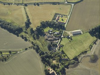Oblique aerial view centred on the remains of the abbey and church and the farmsteading, taken from the NNW.