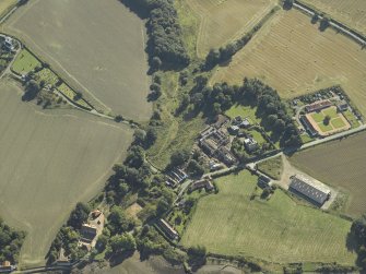 Oblique aerial view centred on the remains of the abbey and church and the farmsteading with the remains of the church and burial-ground adjacent, taken from the NW.
