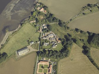 Oblique aerial view centred on the remains of the abbey and church and the farmsteading with the remains of the church and burial-ground adjacent, taken from the S.