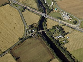 Oblique aerial view centred on the road bridges and tollhouse with the church and burial ground adjacent, taken from the E.