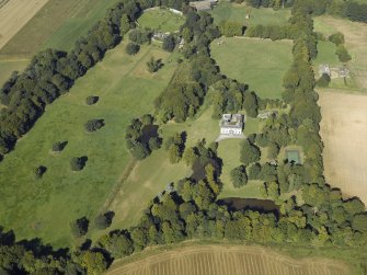 Oblique aerial view centred on the country house, gardens and the stables, taken from the SE.
