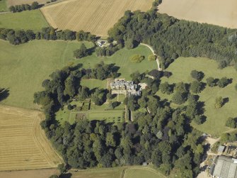 Oblique aerial view centred on the country house and gardens with the cottage adjacent, taken from the SE.