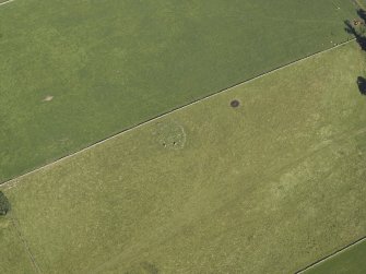 Oblique aerial view centred on the remains of the cairn and stone circle, taken from the SW.