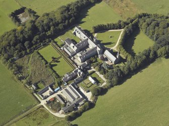 Oblique aerial view centred on the college, church, chapel, dovecot, walled garden and cottage, taken from the E.
