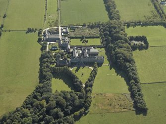 Oblique aerial view centred on the college, church, chapel, dovecot, walled garden and cottage, taken from the N.