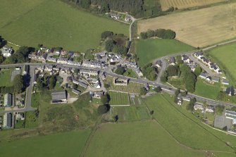 Oblique aerial view of the village centred on the churches, burial-ground and schoolhouse and the ruins of the church, taken from the SSW.