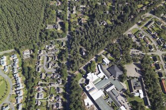 Oblique aerial view centred on the church and the school, taken from the W.