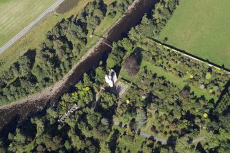 Oblique aerial view centred on the country house, walled garden and suspension bridge, taken from the SW.