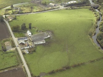 Oblique aerial view centred on the site of the Roman fort and the course of the Antonine Wall with the road bridge adjacent, taken from the E.