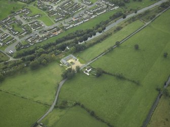 Oblique aerial view centred on the site of the Roman fort and the course of the Antonine Wall and the military way, taken from the NE.