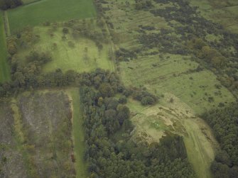 Oblique aerial view centred on the remains of the Roman fort and the course of the Antonine Wall with the remains of the fort adjacent, taken from the E.