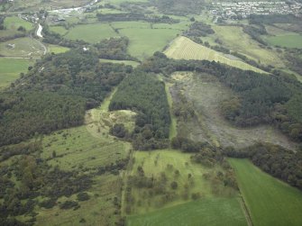 General oblique aerial view centred on the remains of the Roman fort and the course of the Antonine Wall with the remains of the fort adjacent, taken from the W.