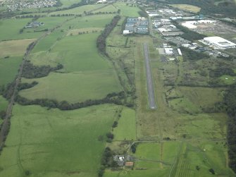 General oblique aerial view centred on the site of the Roman fort, possible Roman fortlet and the course of the Antonine Wall and the Military Way with the airfield and airport adjacent, taken from the W.