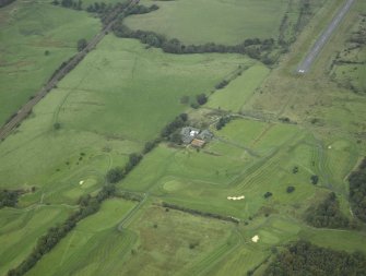 General oblique aerial view centred on the site of the Roman fort, possible Roman fortlet and the course of the Antonine Wall and the Military Way with the airfield and airport adjacent, taken from the SW.