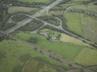 Oblique aerial view centred on the site of the Roman fort and Roman road, taken from the SE.