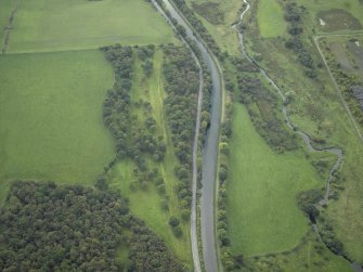 Oblique aerial view centred on the site of the Roman fortlet and the course of the Antonine Wall and the Military Way with the canal and aqueduct adjacent, taken from the NE.