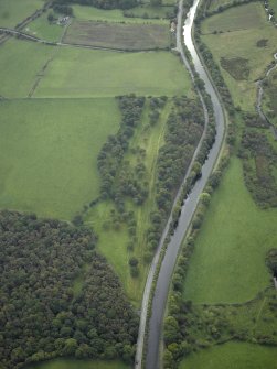 Oblique aerial view centred on the site of the Roman fortlet and the course of the Antonine Wall and the Military Way with the canal and aqueduct adjacent, taken from the NE.
