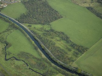 Oblique aerial view centred on the site of the Roman fortlet and the course of the Antonine Wall and the Military Way with the canal and aqueduct adjacent, taken from the WNW.