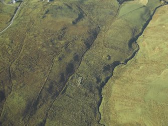 Oblique aerial view centred on the remains of the farmstead and chapel with the remains of the building adjacent, taken from the E.