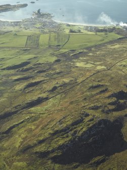 General oblique aerial view centred on the remains of the fort with the village in the distance, taken from the NNE.