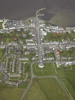 General oblique aerial view of the village centred on the church with the whisky distillery and pier adjacent, taken from the SSE.