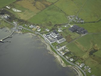 Oblique aerial view of the village centred on the whisky distillery and pier, taken from the ENE.