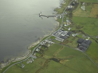 Oblique aerial view of the village centred on the whisky distillery and pier, taken from the NNW.