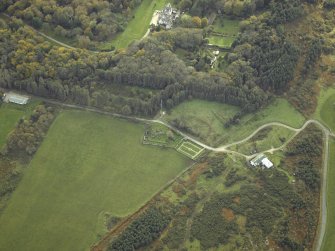 Oblique aerial view centred on the remains of the church and burial-ground with the country house and walled garden adjacent, taken from the N.