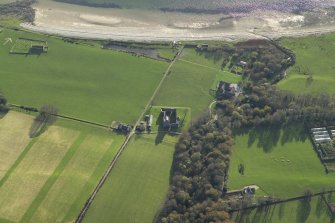 Oblique aerial view centred on the remains of the tower-house with the country house and remains of the church, burial ground and bombing range marker adjacent, taken from the NNE.