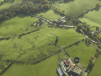 Oblique aerial view centred on the remains of the tower-house and rig with the farmstead adjacent, taken from the N.