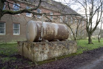 Detail.  Oil tank for oil heating supply mounted on brick base on NE side of Sandhurst Barrack block.