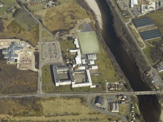 Oblique aerial view centred on the school with the road bridge adjacent, taken from the SW.