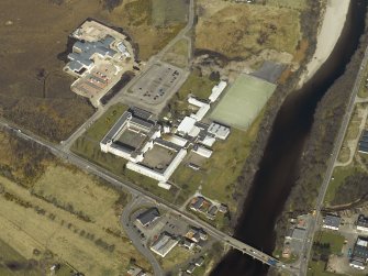 Oblique aerial view centred on the school with the road bridge adjacent, taken from the SSW.