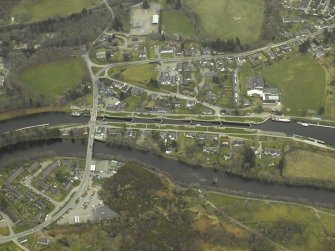 Oblique aerial view of the village centred on the road bridge and swing bridge, taken from the NNW.
