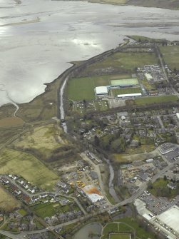Oblique aerial view of the town centred on the hospital, football ground and stadium with the church in the foreground, taken from the WNW.